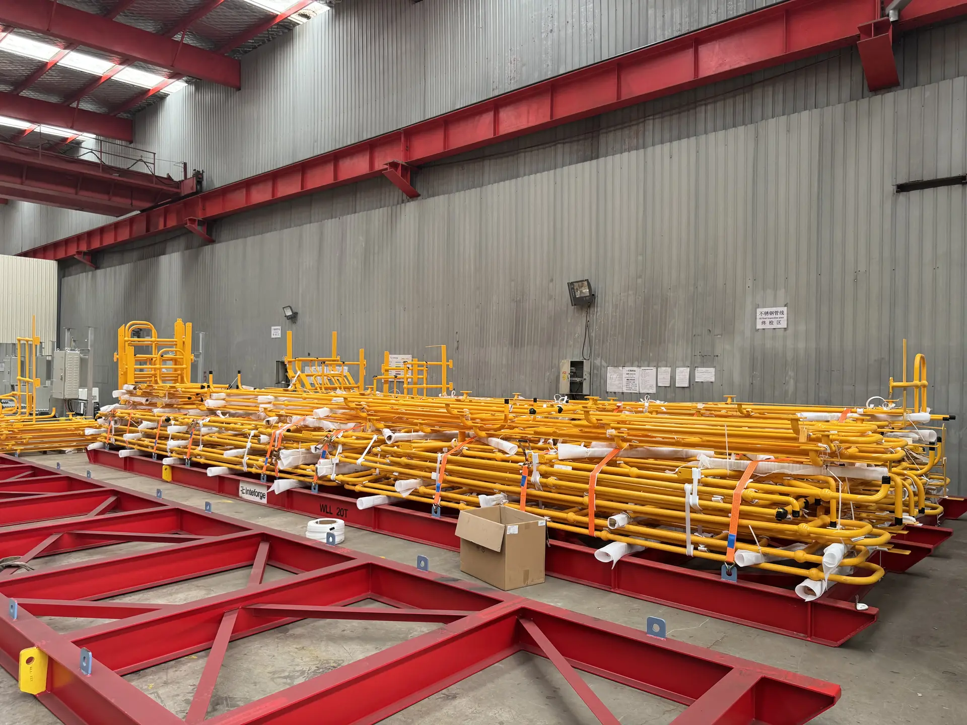 Yellow handrail sections banded in stacks on red steel frames