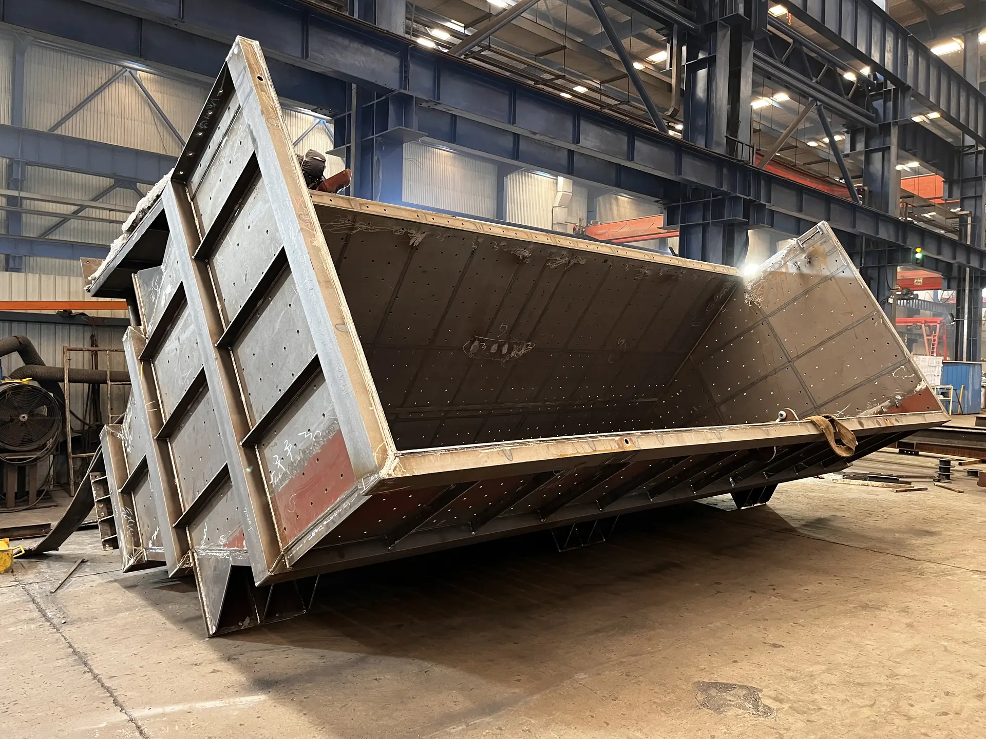 Large steel chute on its side in the workshop, with a ladder at one end