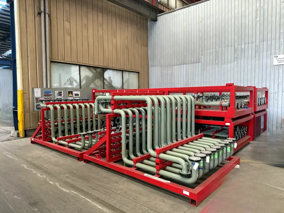 Red framed pipe spool assemblies in grey, bent and lined up on a transport frame in the shop