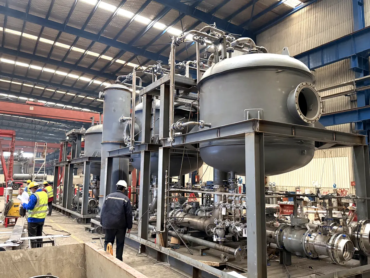 Vessel and pipework skid being assembled on a steel base, with workers in hard hats beside it
